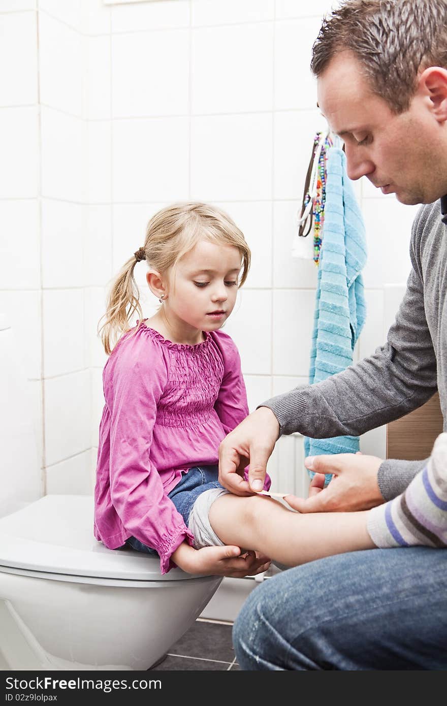 Father put on band-aid on daughters knee. Father put on band-aid on daughters knee