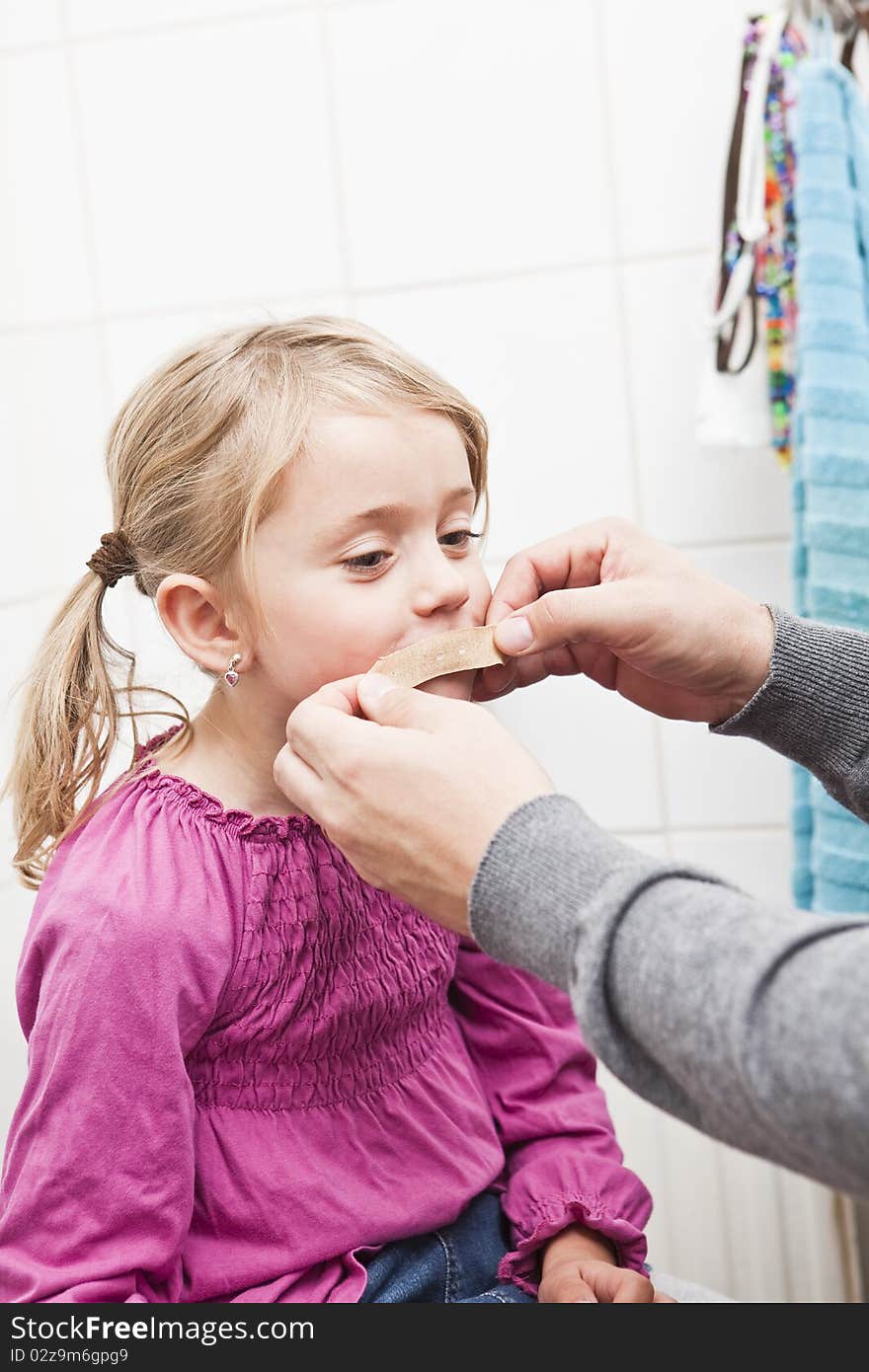 Adult put on Band-Aid on little Girls mouth. Adult put on Band-Aid on little Girls mouth