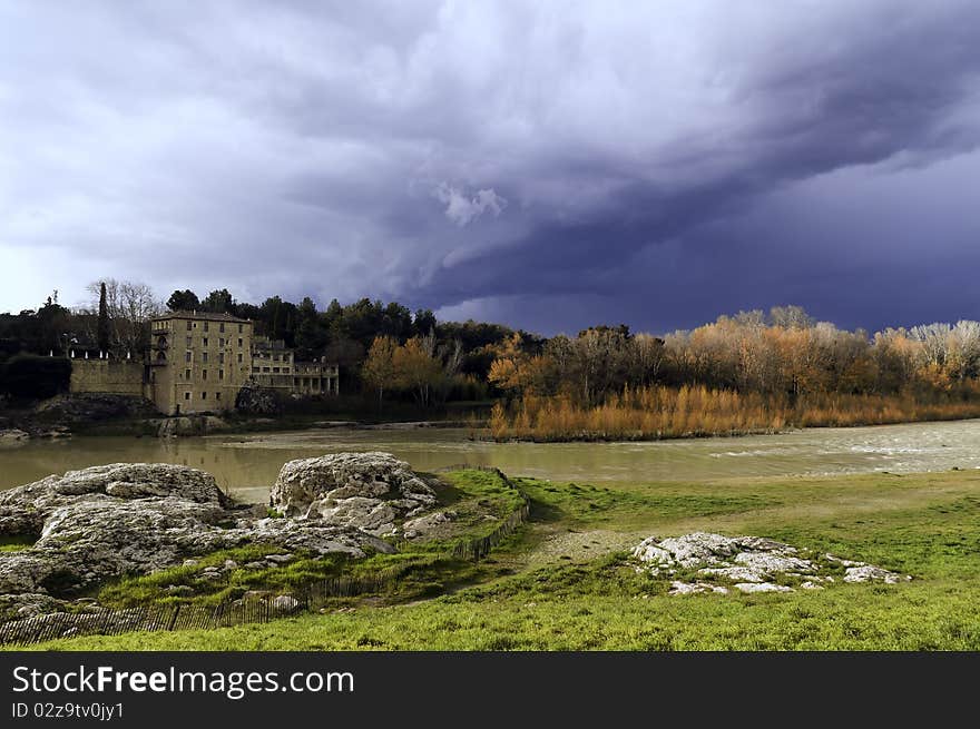 Storm dark clouds over field with building