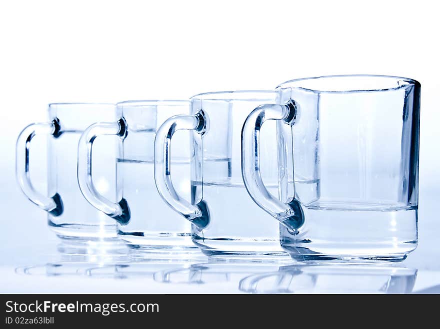 Four blue cups filled with water unevenly. Four blue cups filled with water unevenly