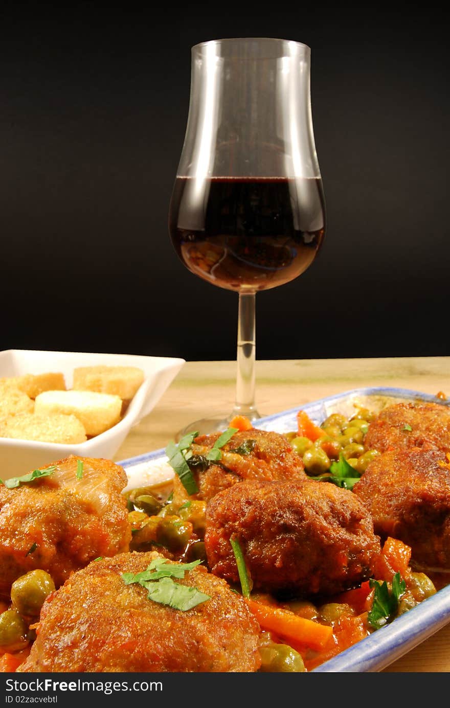 A range of meatballs accompanied by toast and a glass of red wine. A range of meatballs accompanied by toast and a glass of red wine