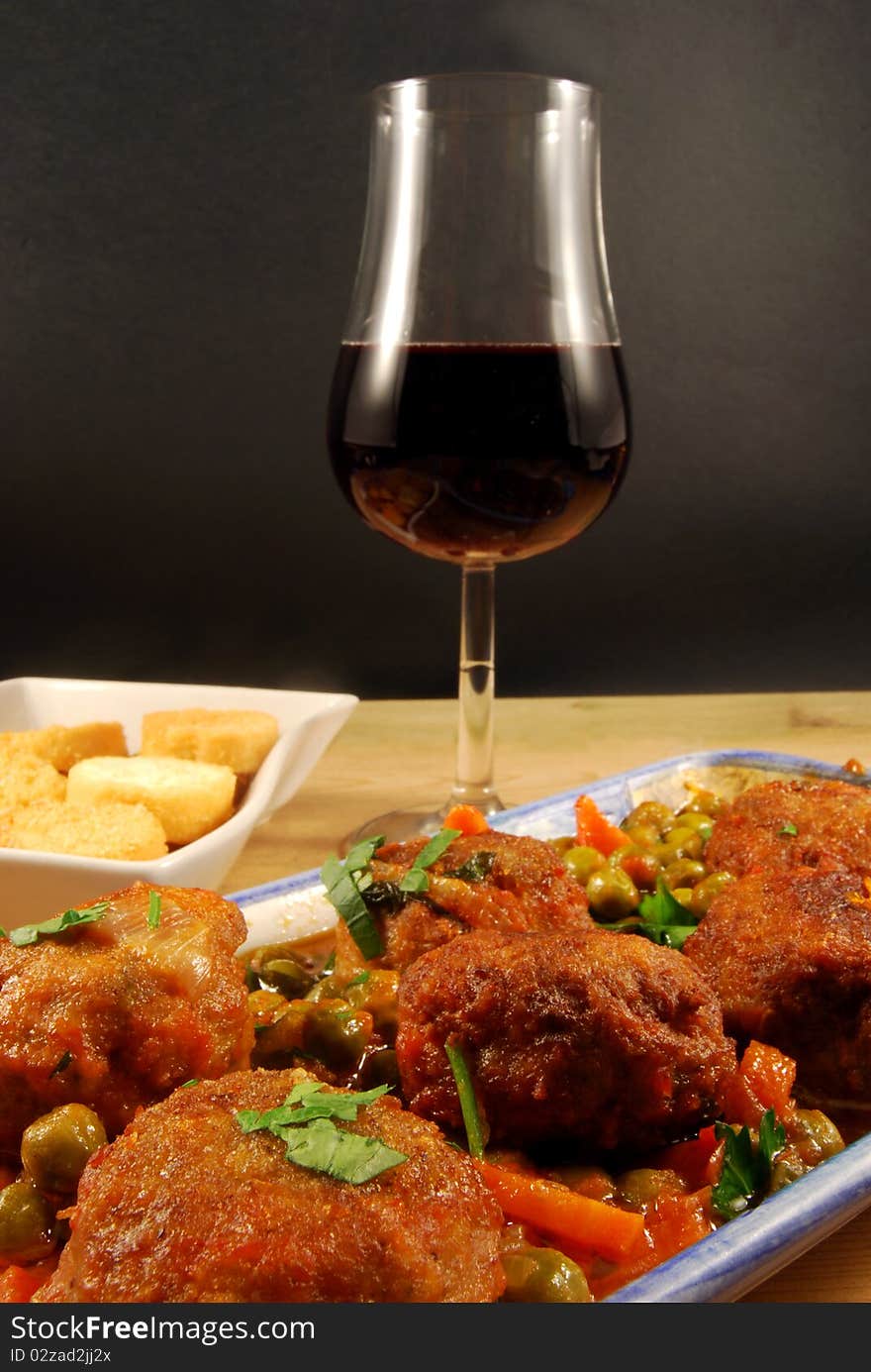 A range of meatballs accompanied by toast and a glass of red wine. A range of meatballs accompanied by toast and a glass of red wine