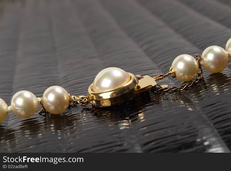 Pearl necklace fragment over black glossy background macro shot