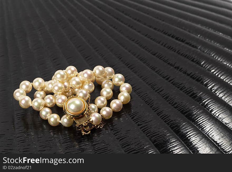 Pearl necklace over black glossy background macro shot