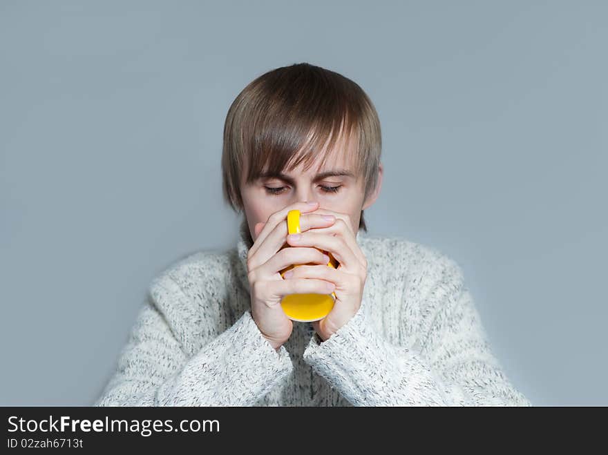 Young man drinking a hot tea from yellow cup