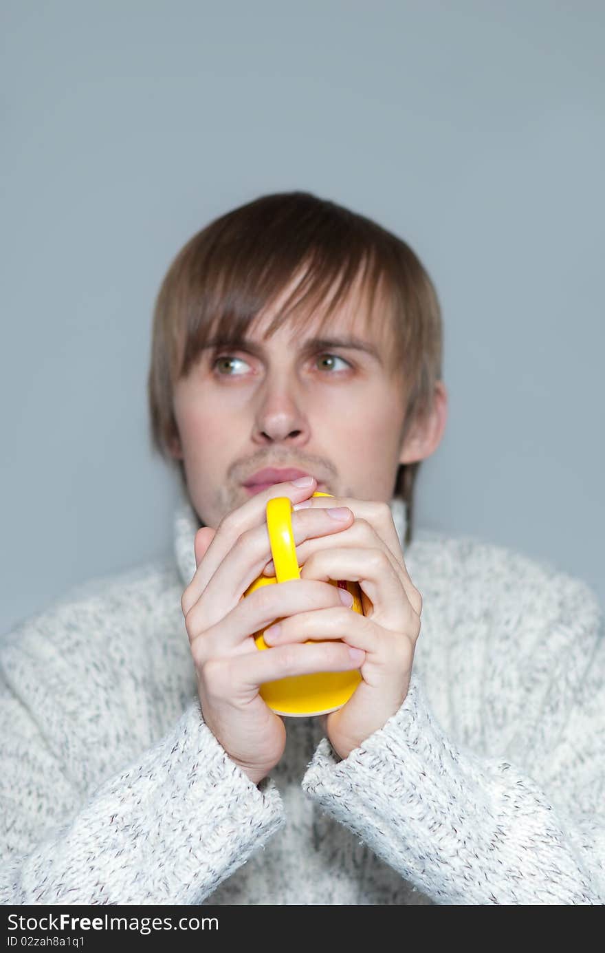 Young man holding a hot tea in yellow cup. Young man holding a hot tea in yellow cup