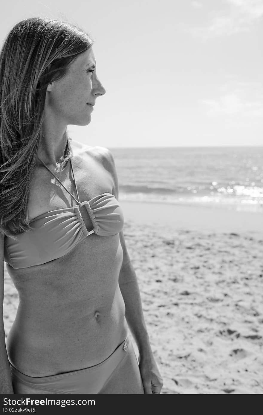 Female in 30's standing on beach in bikini looking away from camera.Black and White image. Female in 30's standing on beach in bikini looking away from camera.Black and White image