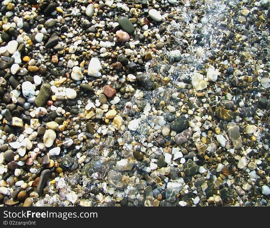 Background.Pebble on a beach in sea water