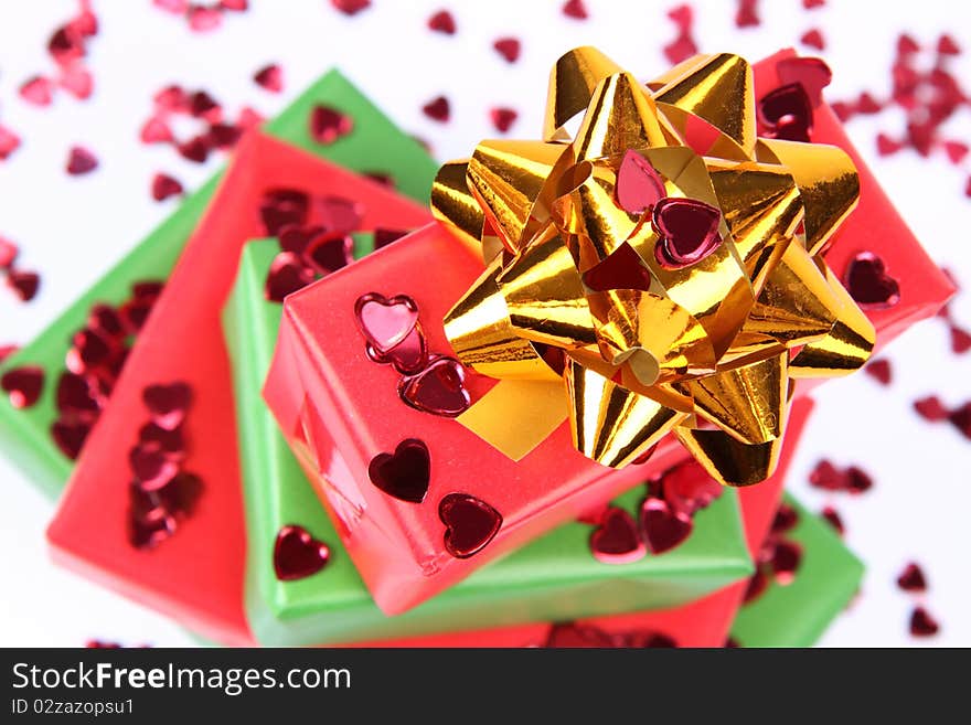 Gifts in green and red wrapping with a golden bow decorated with heart shaped confetti. Gifts in green and red wrapping with a golden bow decorated with heart shaped confetti