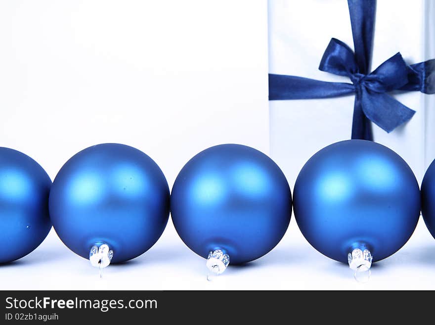 Blue matt christmas balls and a gift in silver wrapping on white background, with space for your text. Blue matt christmas balls and a gift in silver wrapping on white background, with space for your text