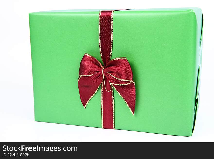 Gift in green wrapping with a red bow on white background