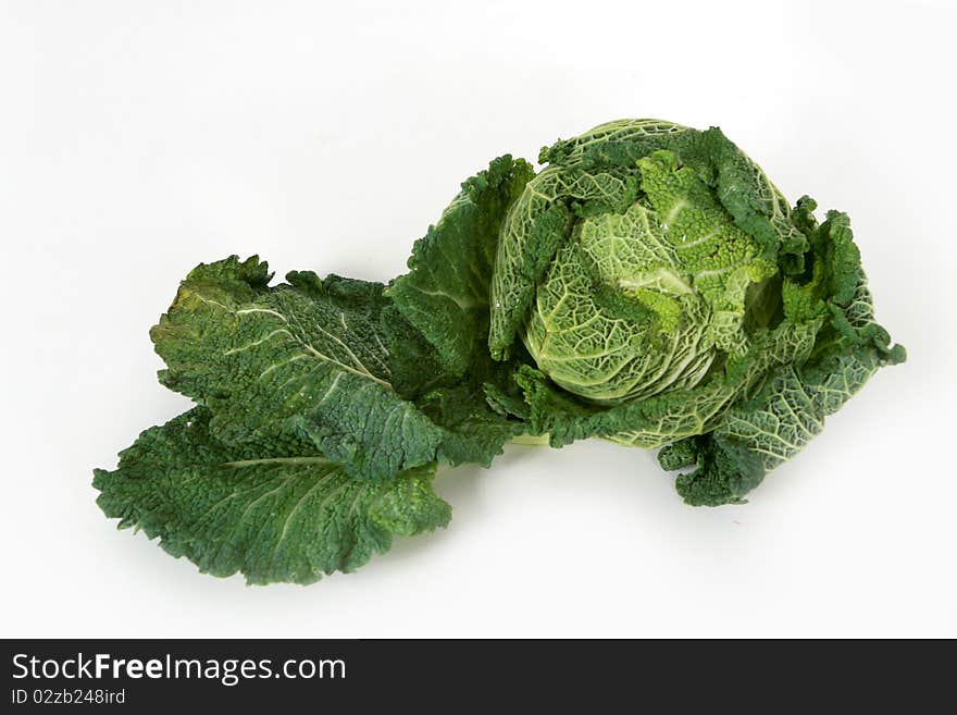 A head of savoy cabbage with leaves on white background