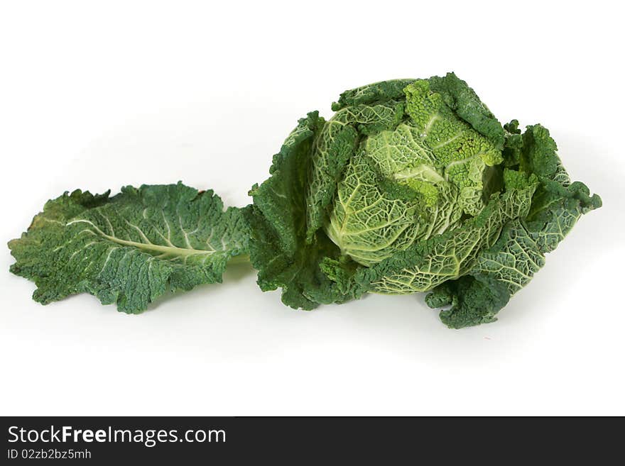 A head of savoy cabbage with leaves on white background