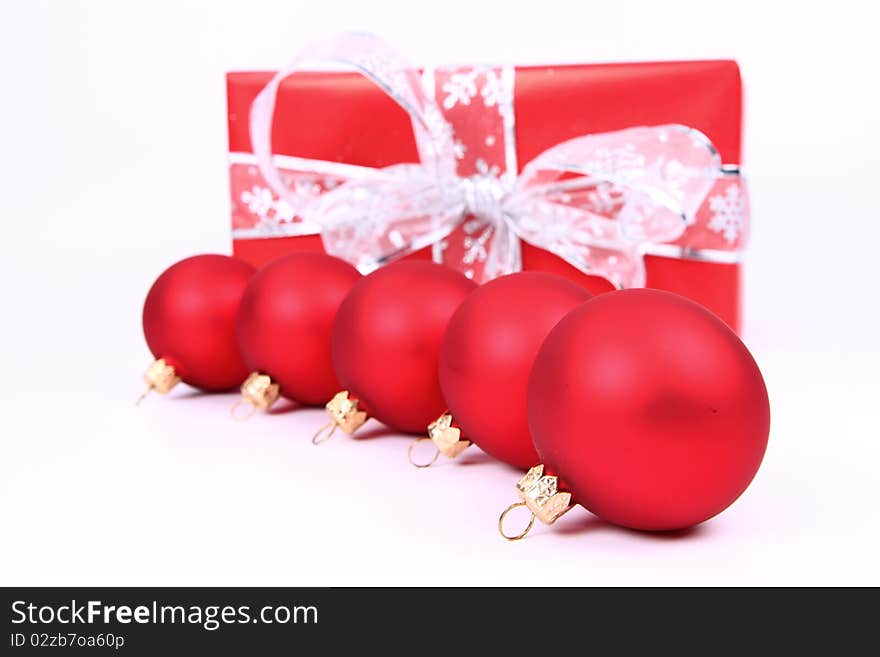 Red matt christmas balls and a gift in red wrapping on white background, with space for your text