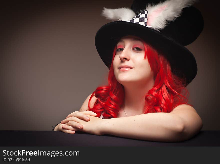 Attractive Red Haired Woman Wearing Bunny Ear Hat on a Grey Background.