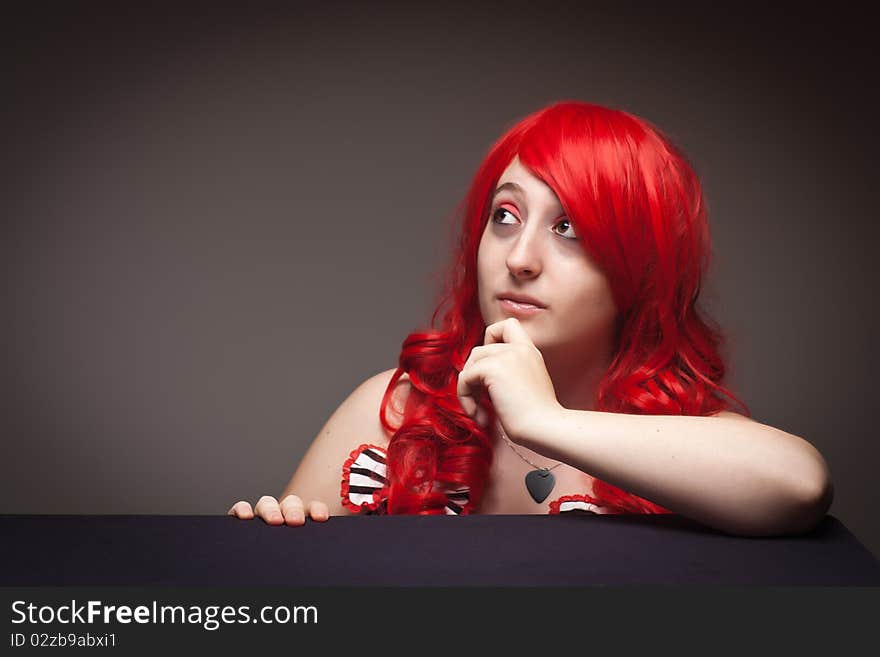 Attractive Red Haired Woman Wearing Bunny Ear Hat on a Grey Background.