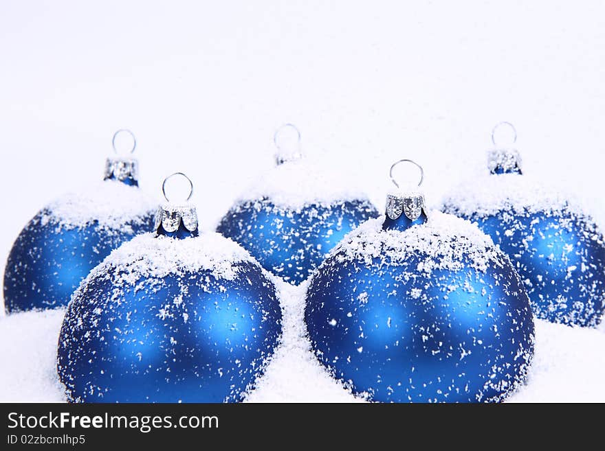 Blue matt christmas balls on snow and with snow falling on white background. Blue matt christmas balls on snow and with snow falling on white background