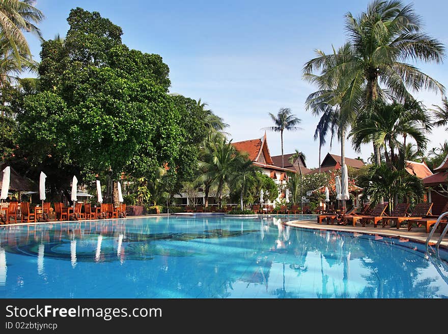 Tropical resort in thai style. Poolside sun lounge exterior.