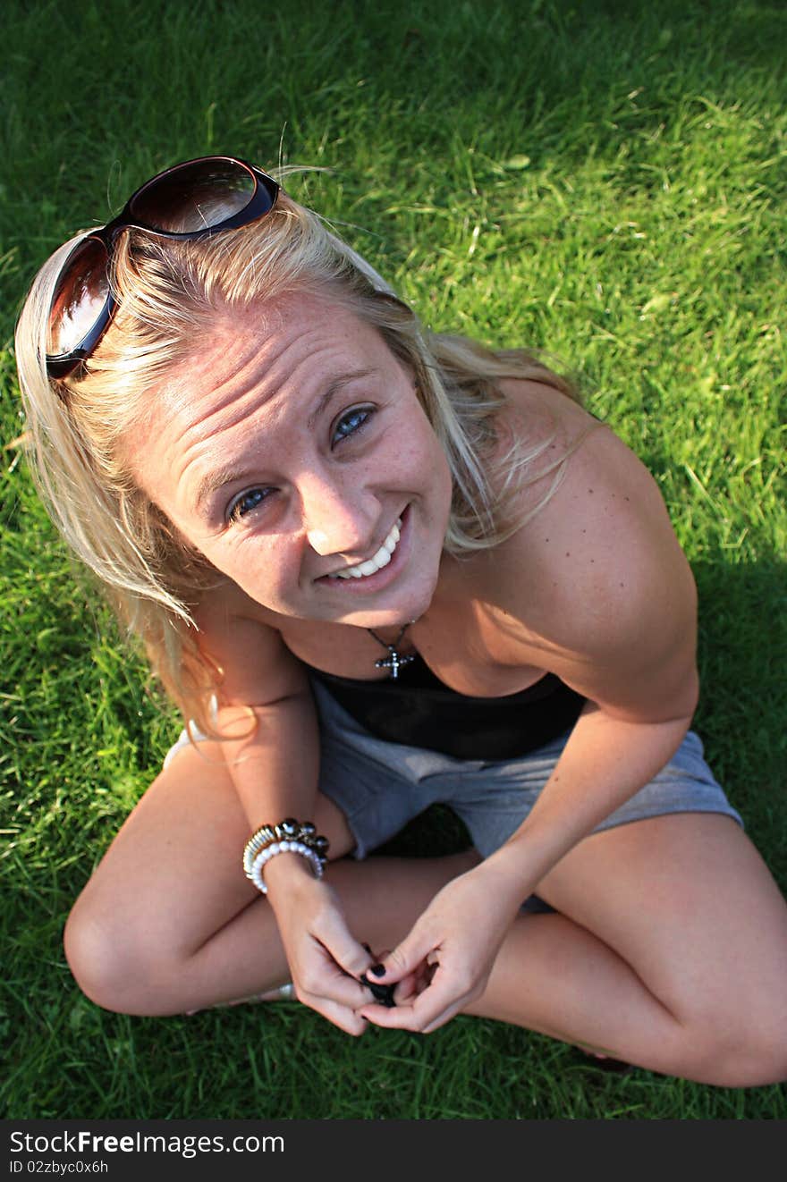 Cross legged woman look up towards the camera and gives of a beaming smile. Cross legged woman look up towards the camera and gives of a beaming smile