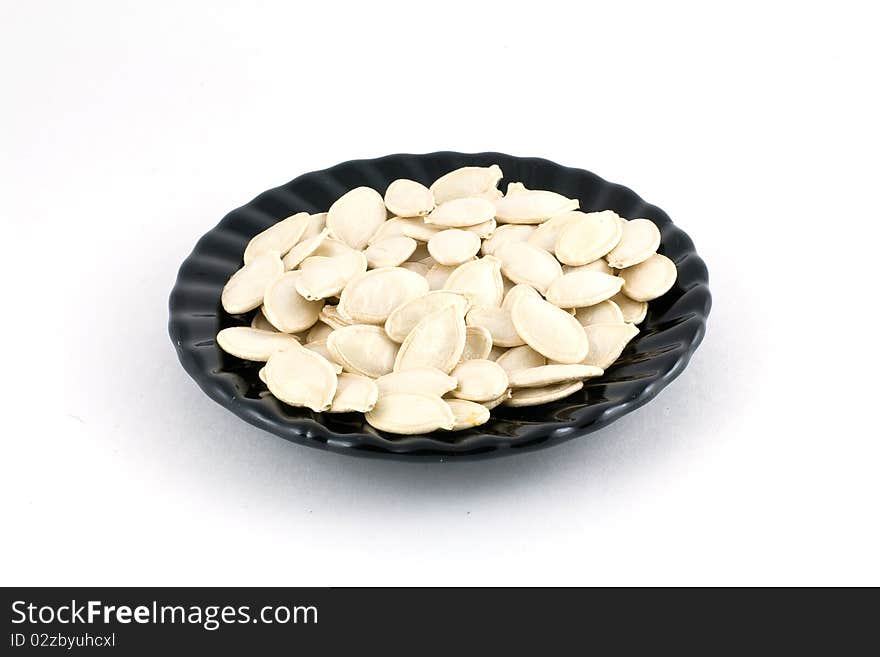 Pumpkin seeds on a glass plate isolated on white background