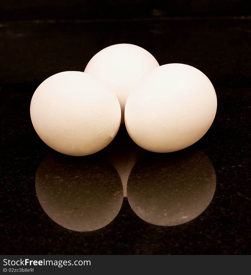 Three chicken eggs on black background