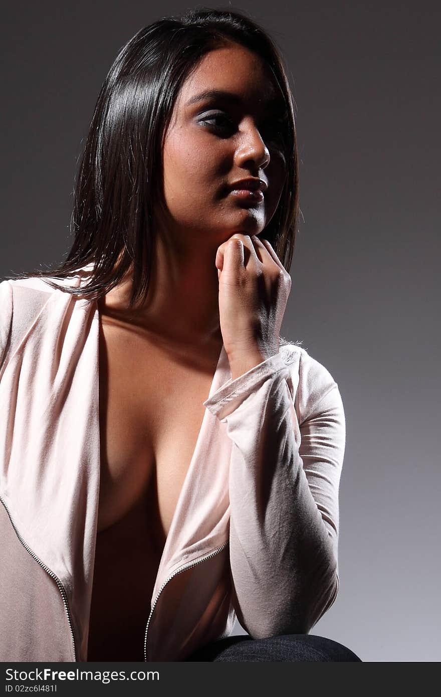 Beautiful and young fashion model in a sultry pose resting chin on her hand, head turned and looking away. Wearing open front long sleeve shirt top showing voluptuous clevage. Beautiful and young fashion model in a sultry pose resting chin on her hand, head turned and looking away. Wearing open front long sleeve shirt top showing voluptuous clevage.