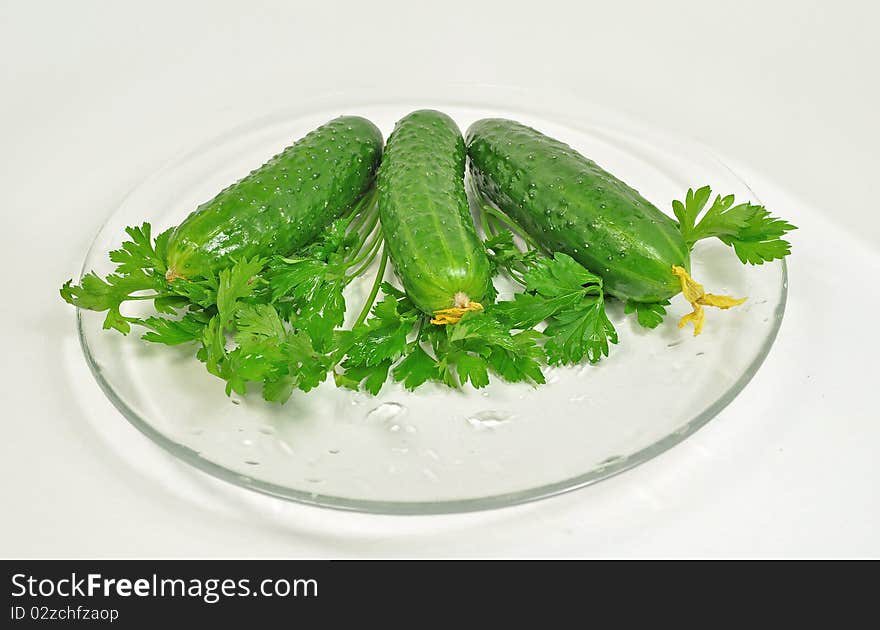 Cucumbers against parsley on a transparent plate. Cucumbers against parsley on a transparent plate