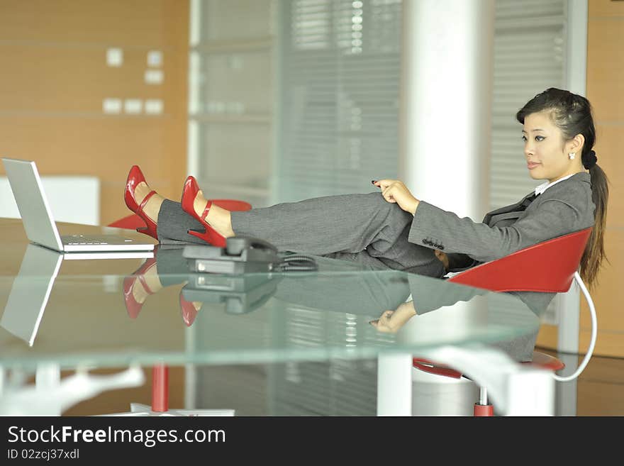 Relaxed Chinese businesswoman, shoes on her desk. Relaxed Chinese businesswoman, shoes on her desk