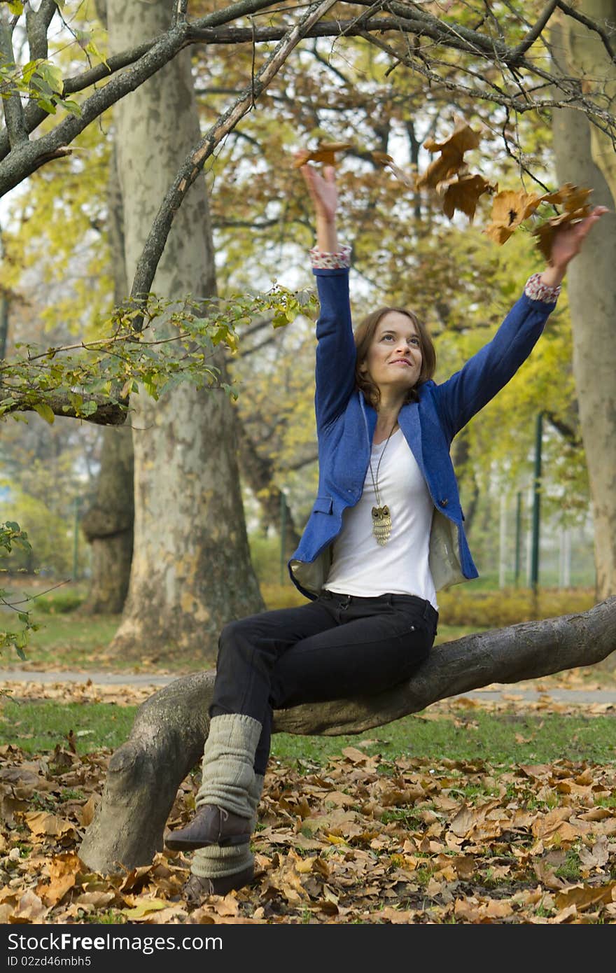 Women in the autumn forest, playing with leaves