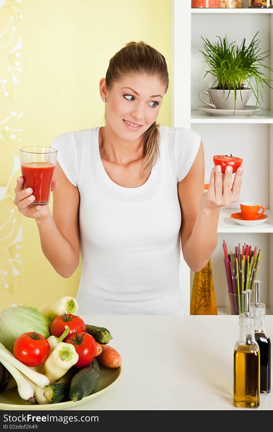 Beauty, young girl holding a glass of juice and a half tomato and smiling