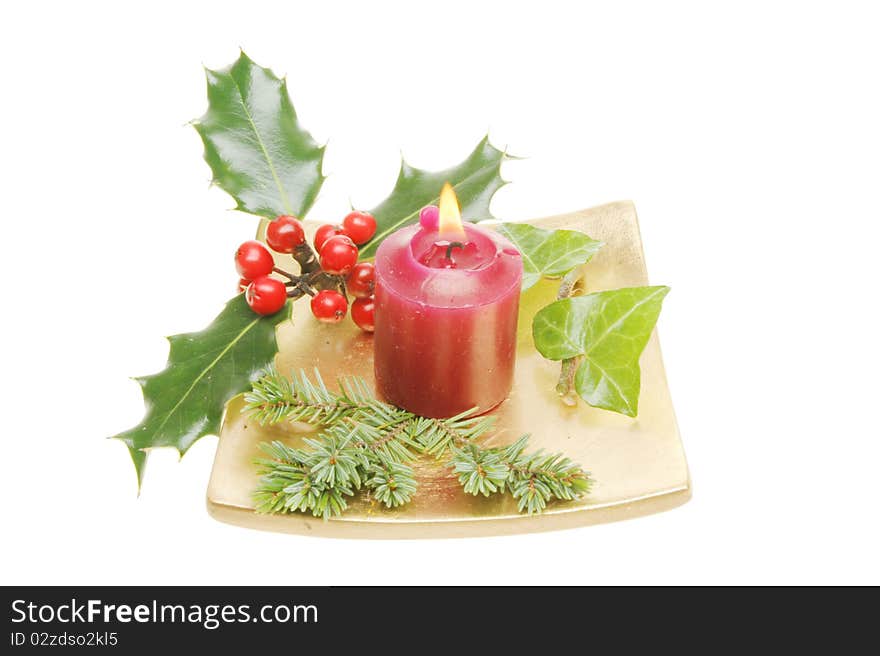 Christmas table decoration, a gold dish with a burning red candle surrounded by holly, ivy and pine needles