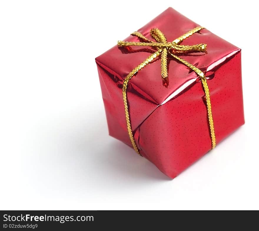 A red box tied with a gold ribbon. A gift for Christmas, Birthday, Wedding, or Valentine's day. Soft focus view.