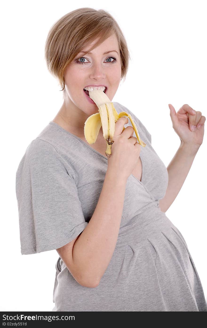 Young pregnant woman eating banana