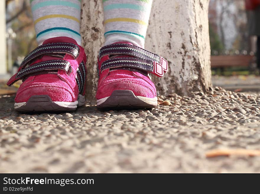 Child in sneakers cost around a tree on the shingle. Child in sneakers cost around a tree on the shingle