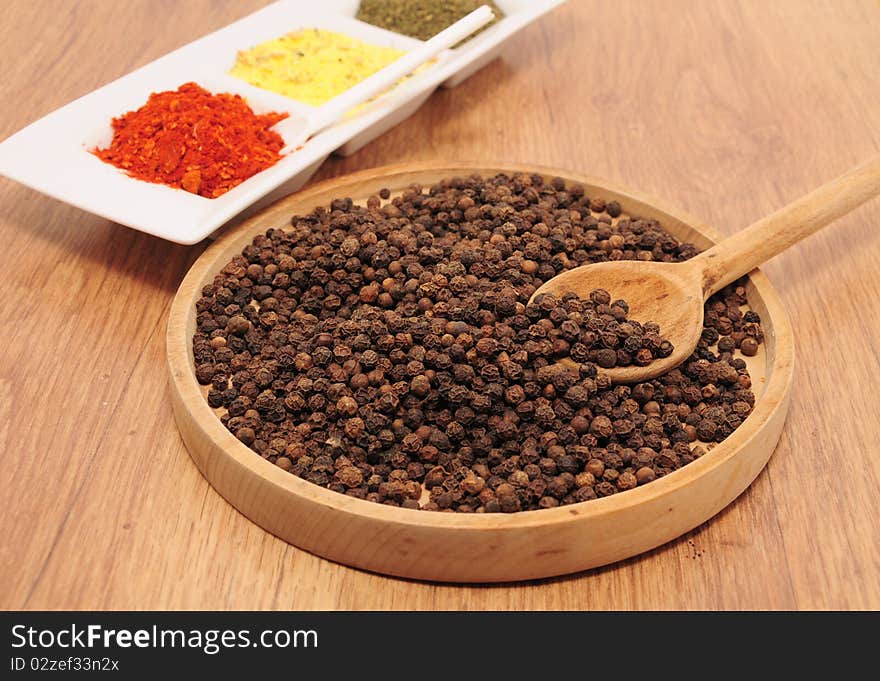 Peppercorns on the table in a wooden bowl. Peppercorns on the table in a wooden bowl