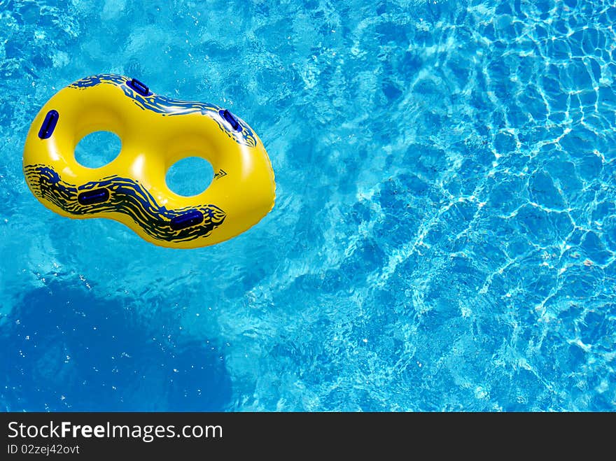 Yellow rubber ring floating in blue water