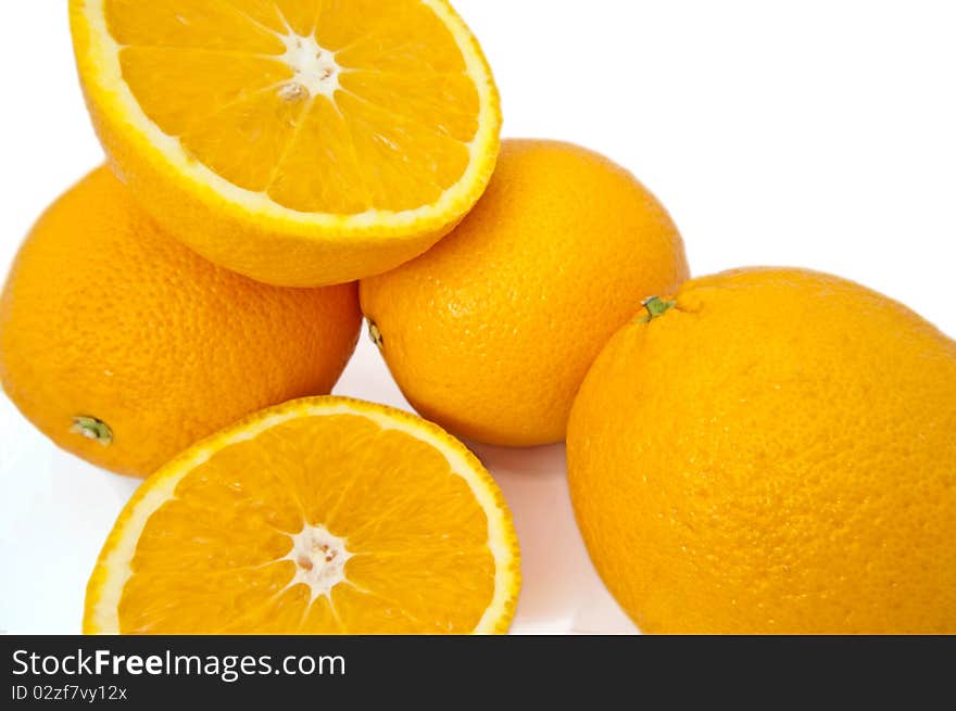 Close up capturing several fresh whole and cut oranges over white. Close up capturing several fresh whole and cut oranges over white.