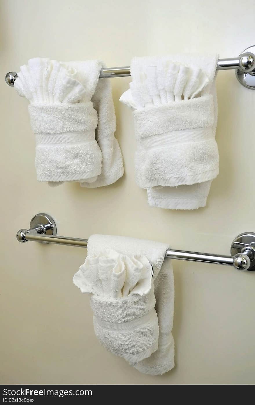 Clean and folded white towels hanging in the bathroom.