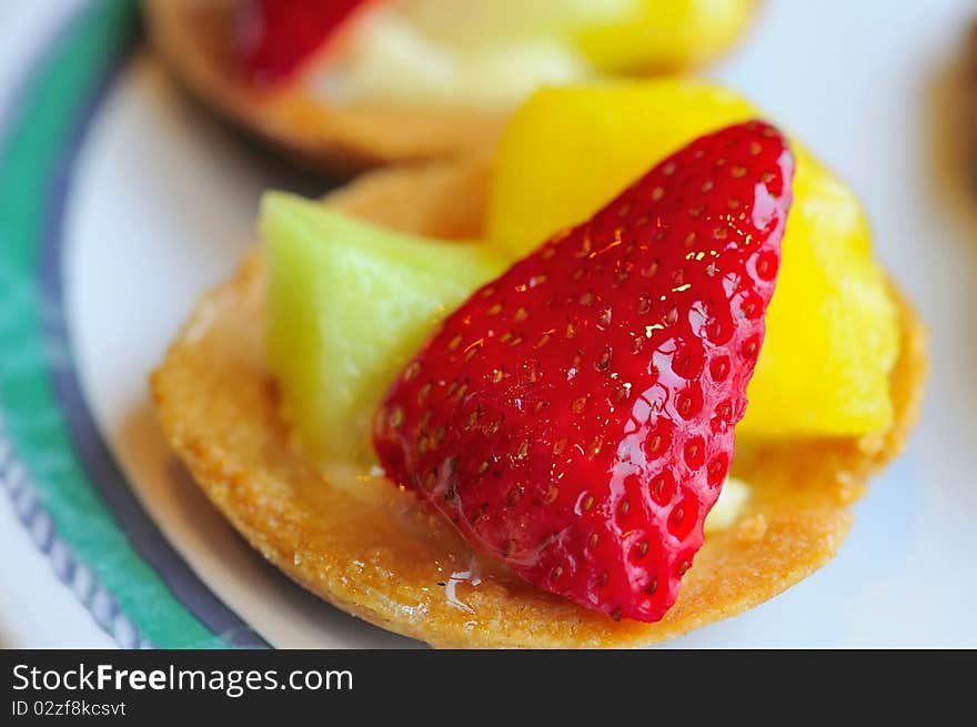 Healthy fruit tarts prepared with different colored cut fruits such as strawberries and honey dew.