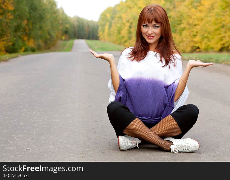 Beautiful smiling woman is sitting on the road