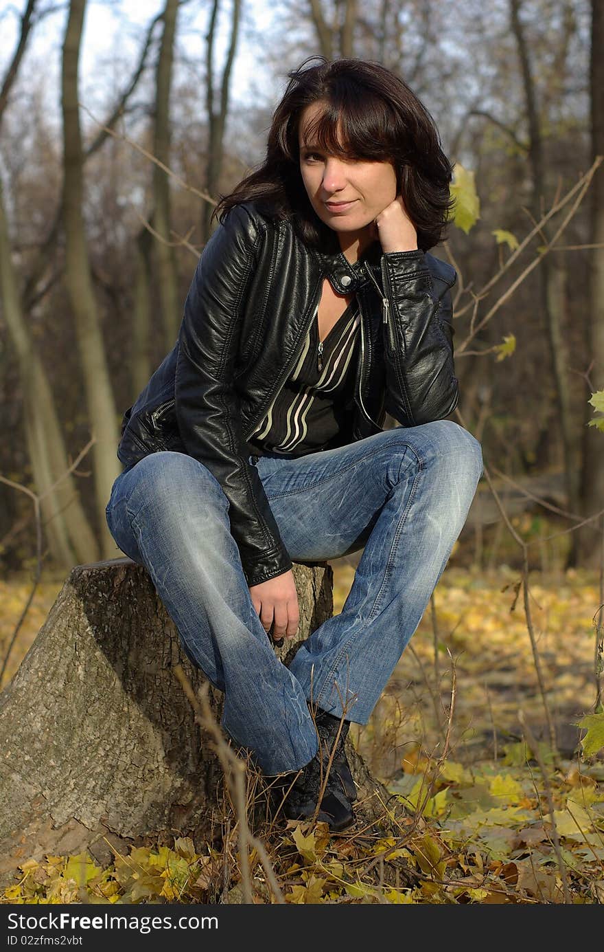 Girl sitting on a stump in an autumn park