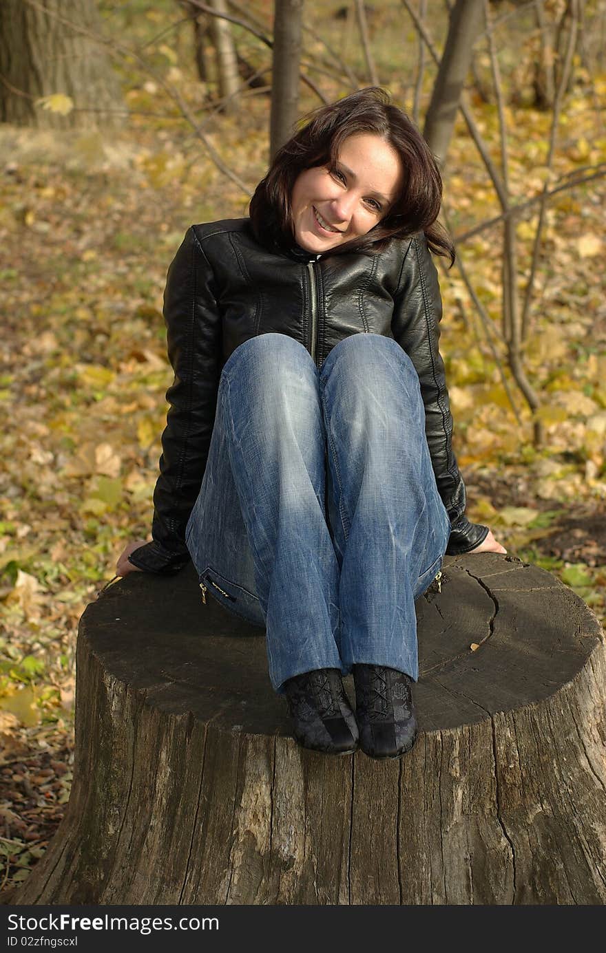 Woman sitting on a stump in an autumn park. Woman sitting on a stump in an autumn park