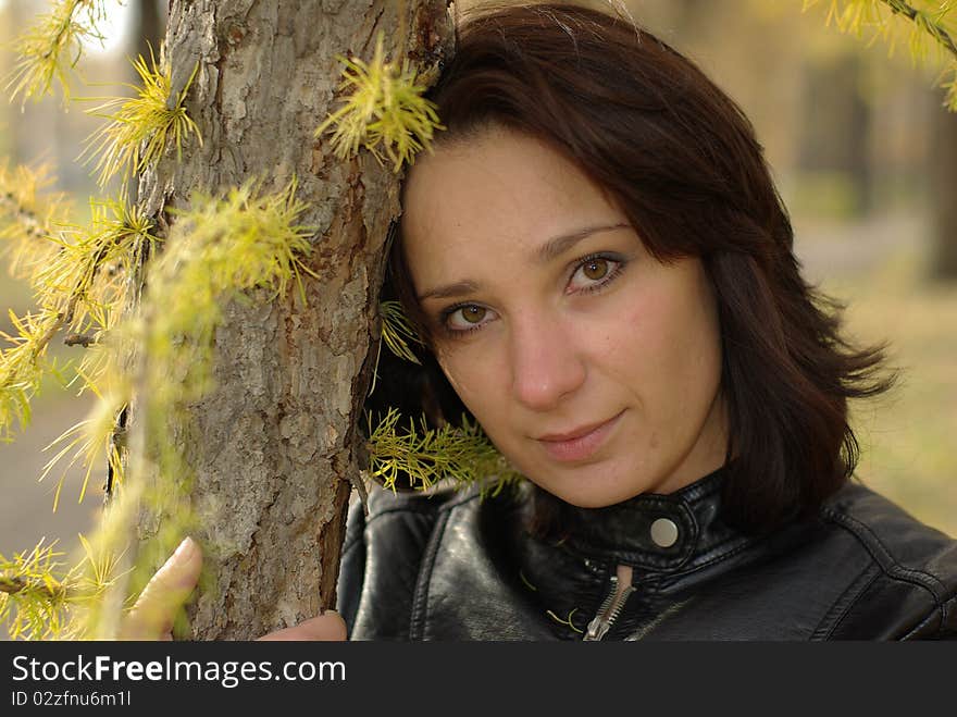 Girl in a coniferous forest leaning against a fir-tree