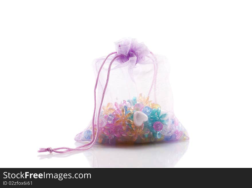 Colored beads in a lavender bag isolated on white