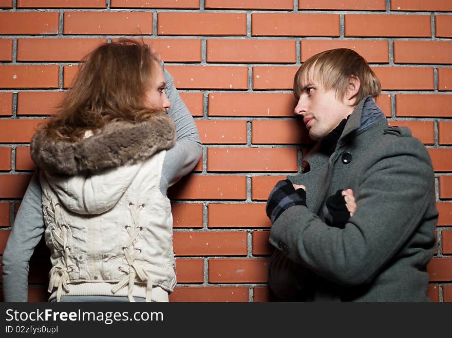 Young couple at the brick wall at fall season