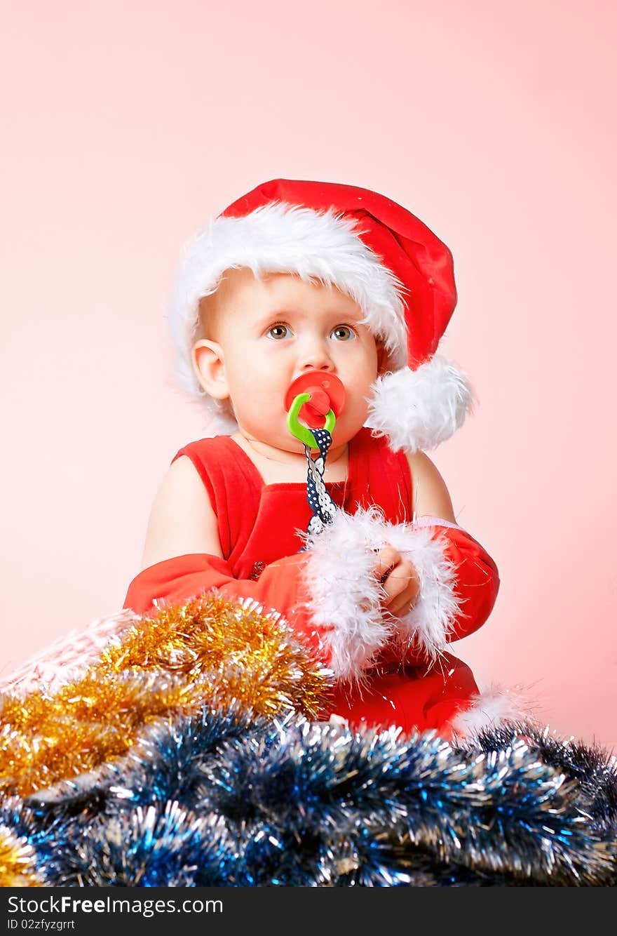 Baby in Santa Claus hat on pink background