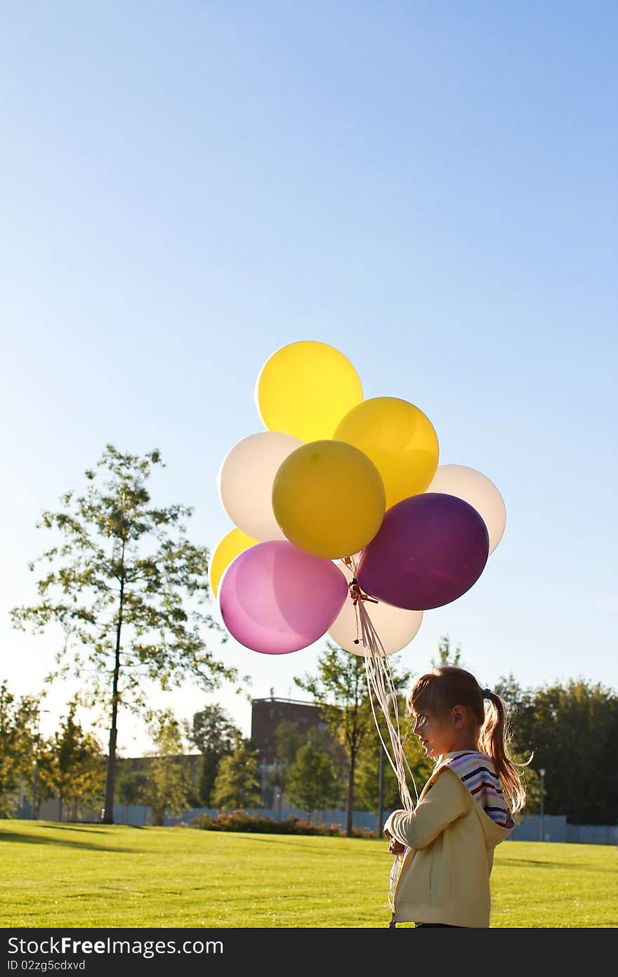 A child with multi-colored balloons