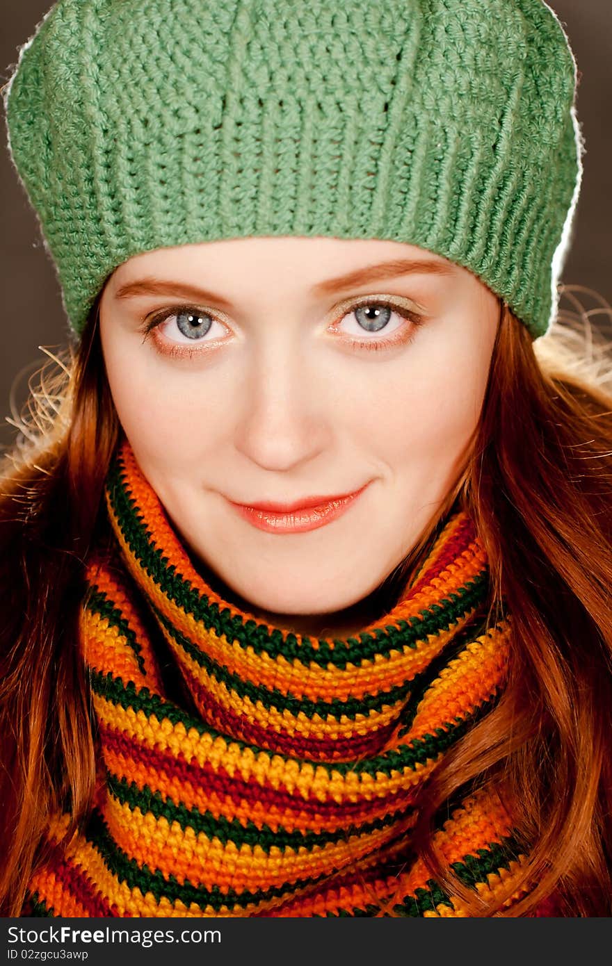 Young beautiful redhead girl in a green beret and a colorful autumn knitted scarf. Young beautiful redhead girl in a green beret and a colorful autumn knitted scarf