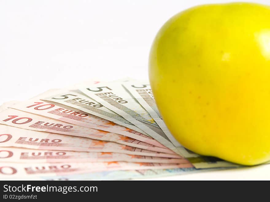 Green apple lying on the banknotes of different denomination, lying like a fan. on a white background, close-up. Green apple lying on the banknotes of different denomination, lying like a fan. on a white background, close-up