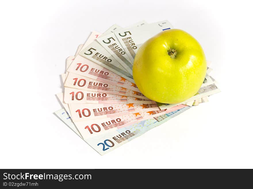 Green apple lying on the banknotes of different denomination, lying like a fan. on a white background. Green apple lying on the banknotes of different denomination, lying like a fan. on a white background